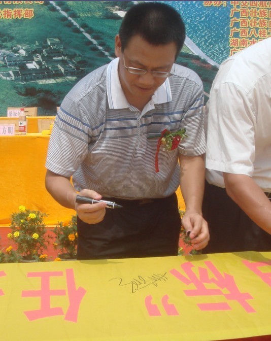 廣西新港灣公司副總經(jīng)理姚方明在“奮戰100天，如期實(shí)現魚(yú)梁工程截流、通航、發(fā)電‘三大目標’”橫幅上簽字